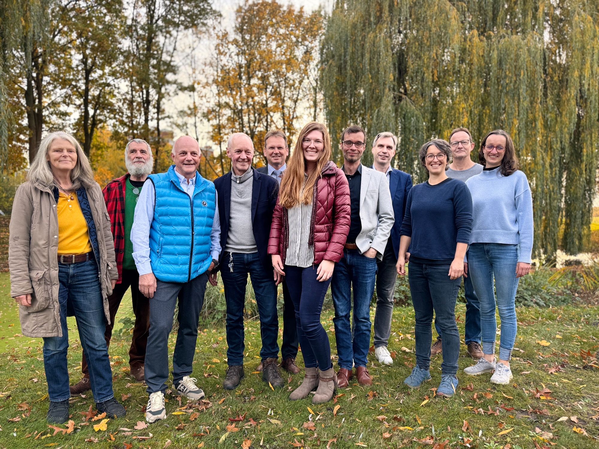 Die elf Personen, die an der Abschlussveranstaltung des Arbeitskreises "Sorgsamer Umgang mit Trinkwasser in der Region Bremen" teilgenommen haben, haben sich für ein Gruppenbild im Garten der Geschäftsstelle des Trinkwasserverbandes Verden aufgestellt. Alle lächeln in die Kamera. 